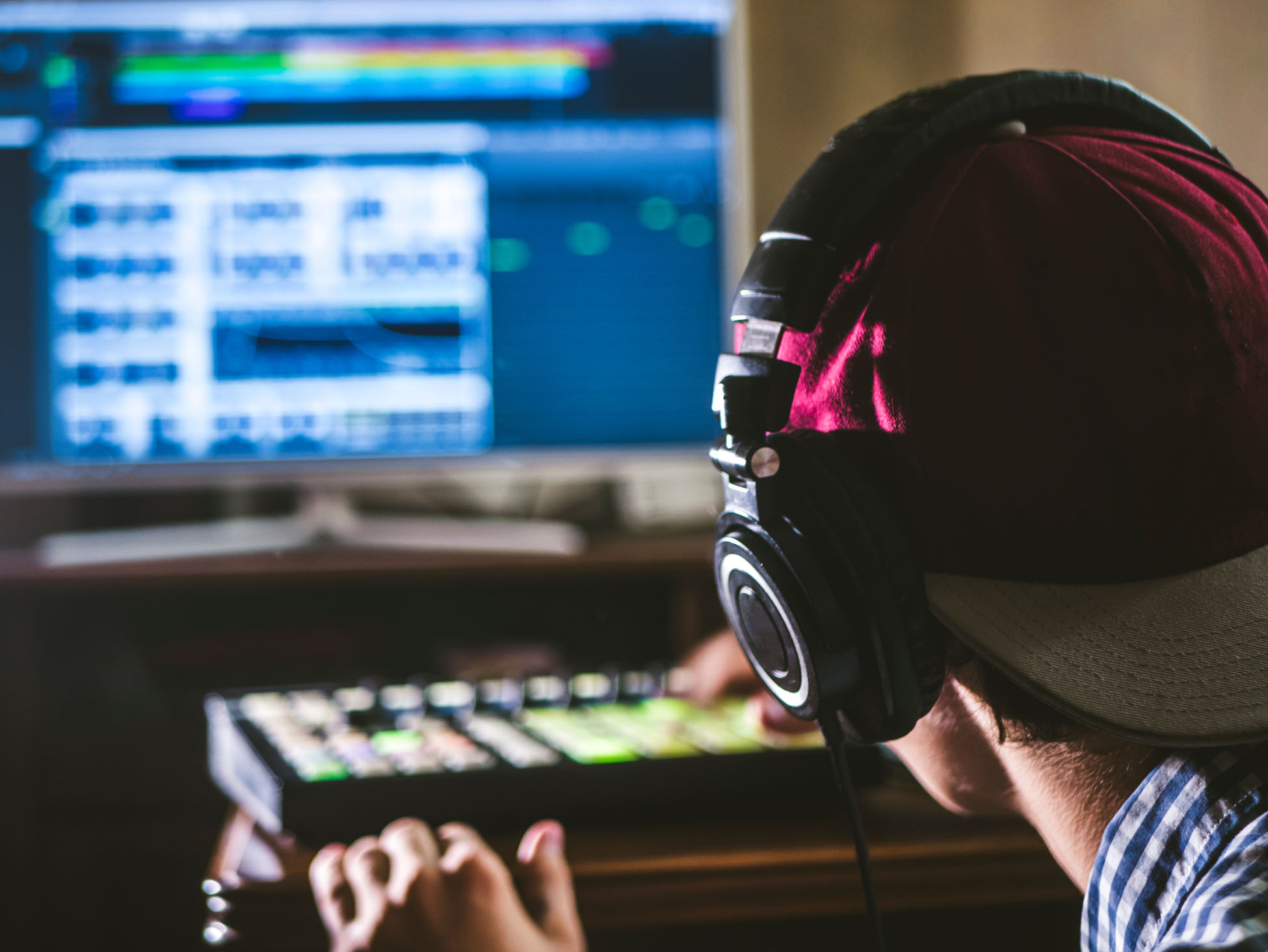 back view of sound engineer in snapback and holding headphones on head monitoring music in studio